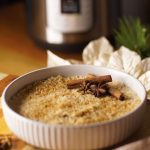 plate of Puerto Rican rice pudding garnished with cinnamon and anise star with instant pot on back ground.