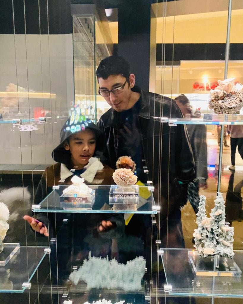 Yessi's husband and son looking at gems in the gallery at Carnegie Natural History Museum