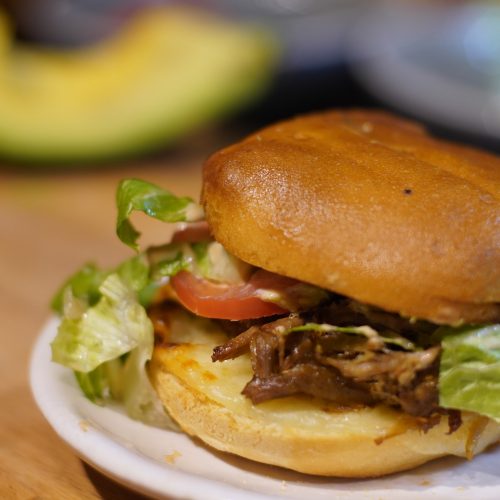 Picture of a peril Puerto Rican sandwich with a slice of avocado on the background.