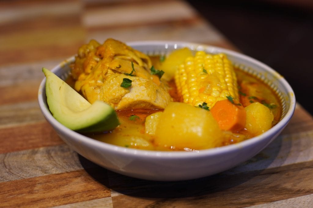 Bowl of Puerto Rican Asopao de pollo served with a slice of avocado.