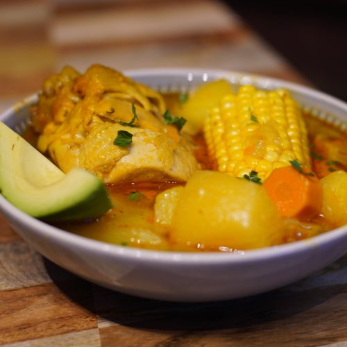 Bowl of Puerto Rican Asopao de pollo served with a slice of avocado.