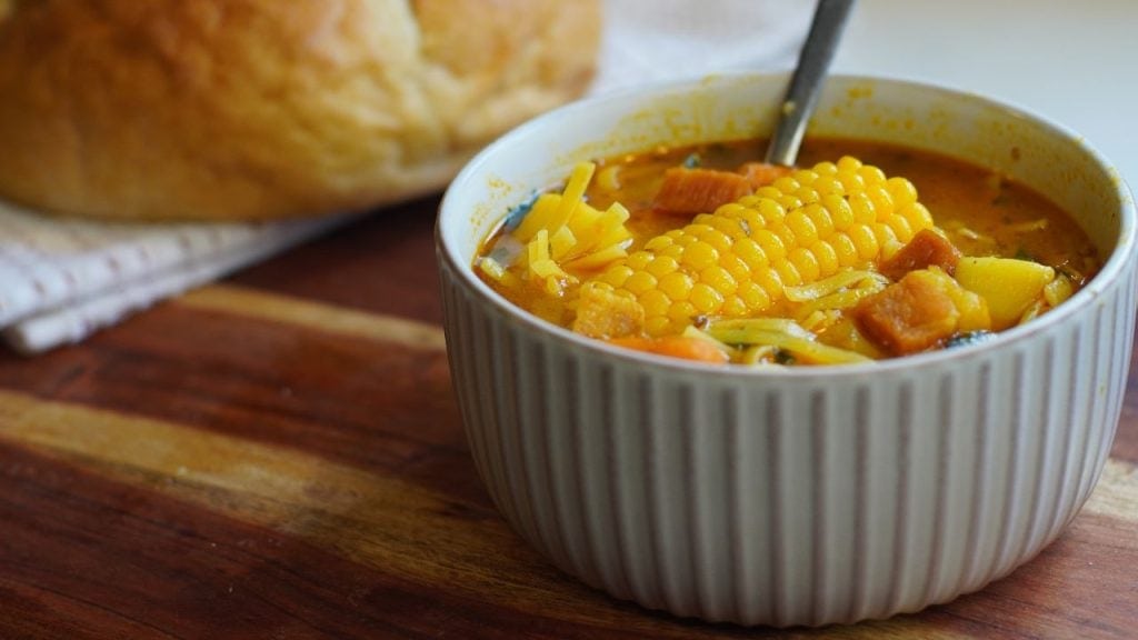 Bowl of Puerto Rican Ham soup with a piece of bread in background