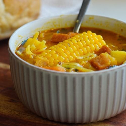 Bowl of Puerto Rican Ham soup with a piece of bread in background