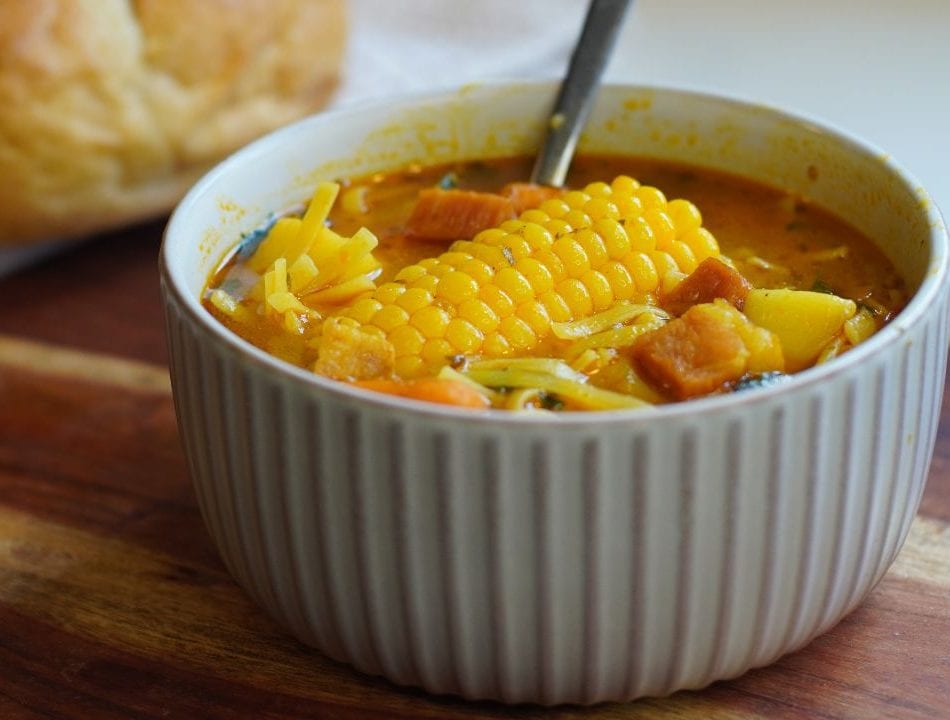 Bowl of Puerto Rican Ham soup with a piece of bread in background