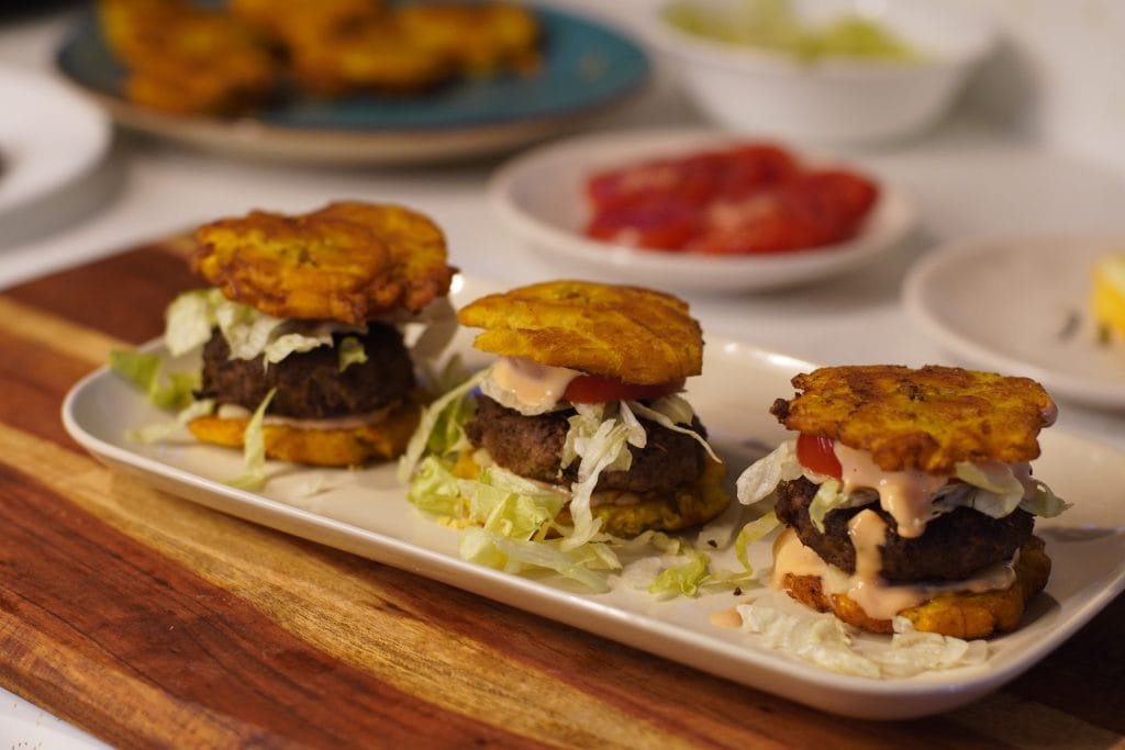 3 Puerto rican jibarito sliders on a square plate with a wooden cutting board underneath